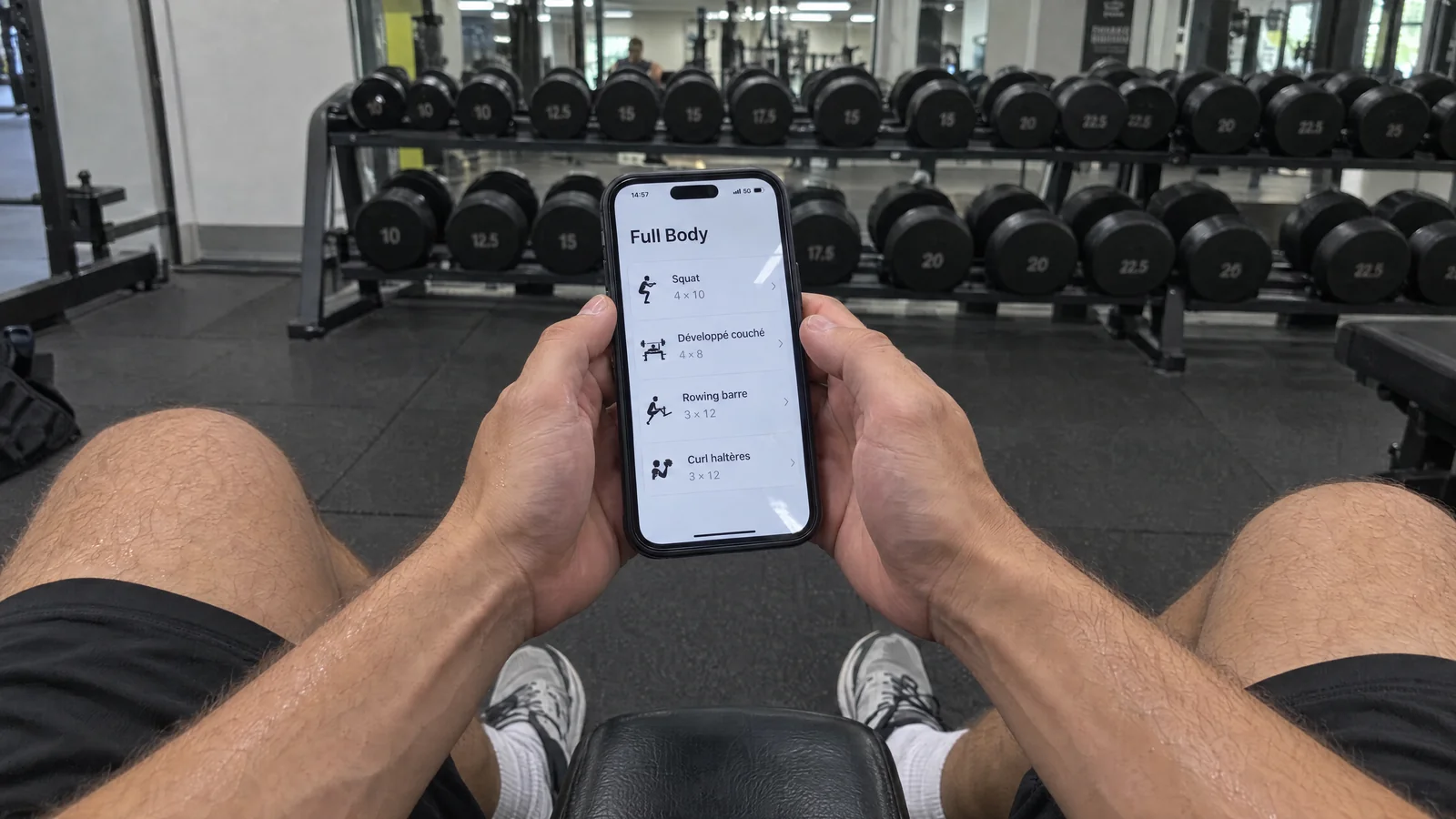 Séance Full Body affichée sur l’application Enzo Coaching, smartphone en main devant les haltères